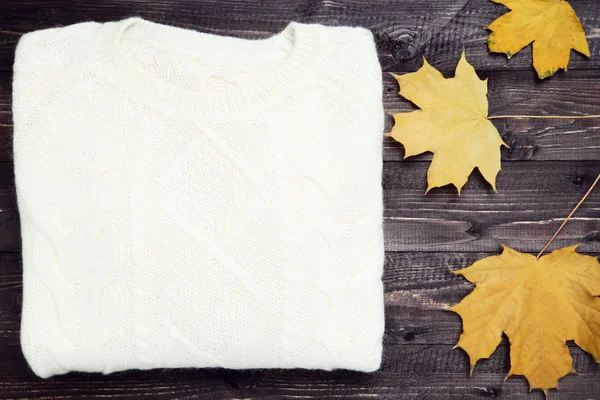 Gevouwen trui met herfst blaadjes op houten tafel — Stockfoto