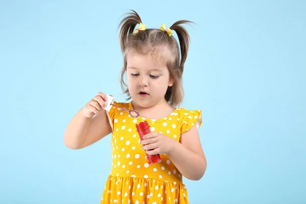 Söt liten flicka blåser tvål bubblor på blå bakgrund — Stockfoto