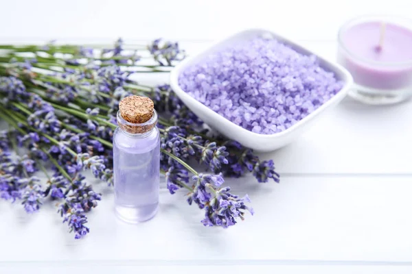 Lavendelblüten mit Öl in der Flasche und Salz in der Schüssel auf weißem — Stockfoto