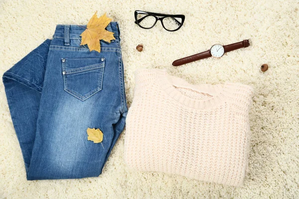 Pull tricoté avec jeans et feuilles d'érable sur tapis blanc — Photo