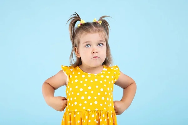 Söt liten flicka i gul klänning på blå bakgrund — Stockfoto