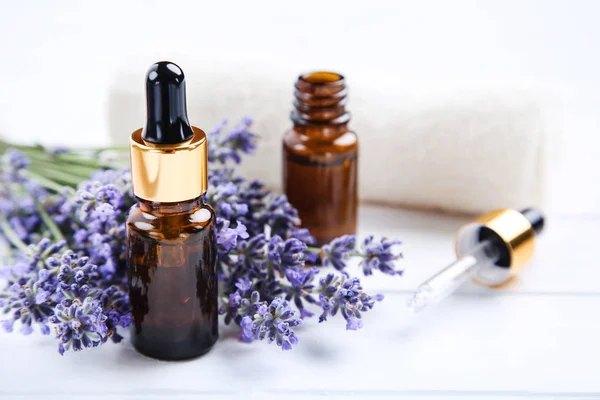 Lavendelblüten mit Öl in Flaschen und Handtuch auf weißem Holz — Stockfoto