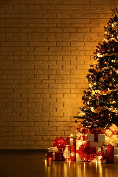 Árbol de Navidad con decoraciones y cajas de regalo sobre fondo de pared de ladrillo — Foto de Stock