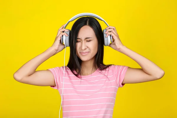 Mooie vrouw met koptelefoon op gele achtergrond — Stockfoto