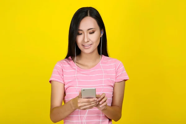 Belle jeune femme avec smartphone et écouteurs sur ba jaune — Photo