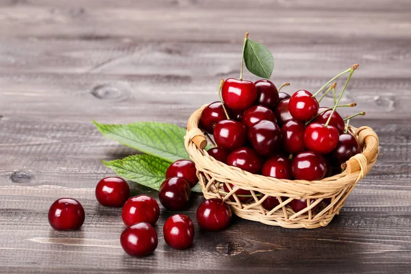 Sweet cherries with basket on wooden table