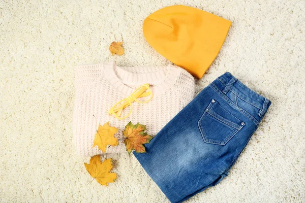 Jersey de punto con jeans, gorro y hojas de arce sobre alfombra blanca —  Fotos de Stock