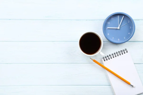 Runde Uhr mit Tasse Kaffee und Notizblock auf Holztisch — Stockfoto