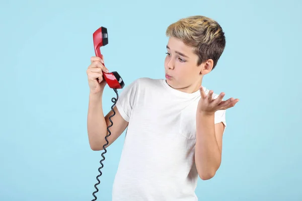Mladý chlapec s telefonem na modrém pozadí — Stock fotografie