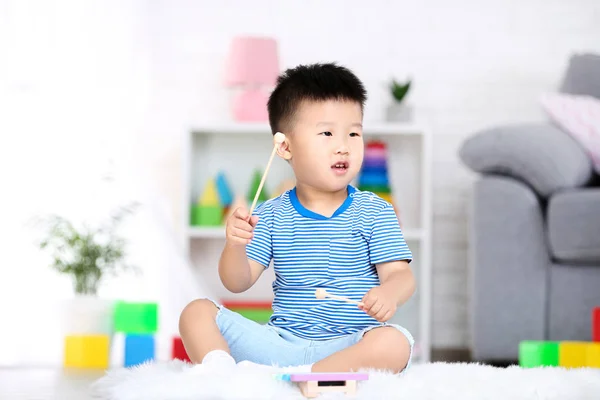 Bello ragazzo seduto e giocando sul giocattolo musicale a casa — Foto Stock