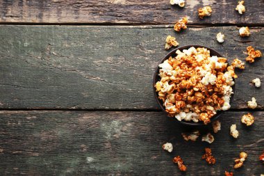 Ahşap masa üzerinde bir kapta karamelli patlamış mısır