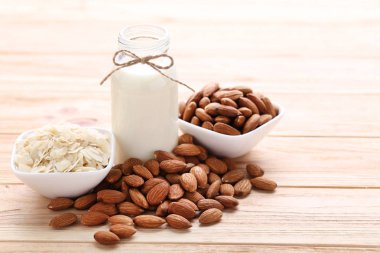 Kahverengi ahşap masa üzerinde şişe badem ve süt