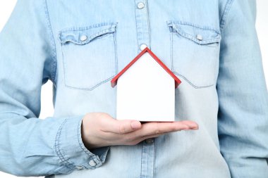 Ahşap ev modelini tutan kadın.