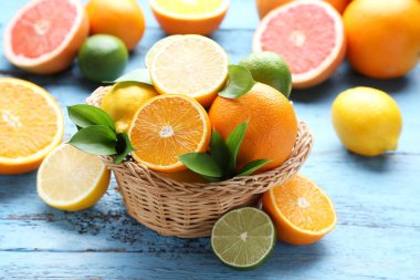 Mavi ahşap masa üzerinde sepet yeşil yapraklı narenciye