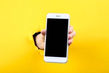 Sarı yırtık kağıttan el tutan akıllı telefon