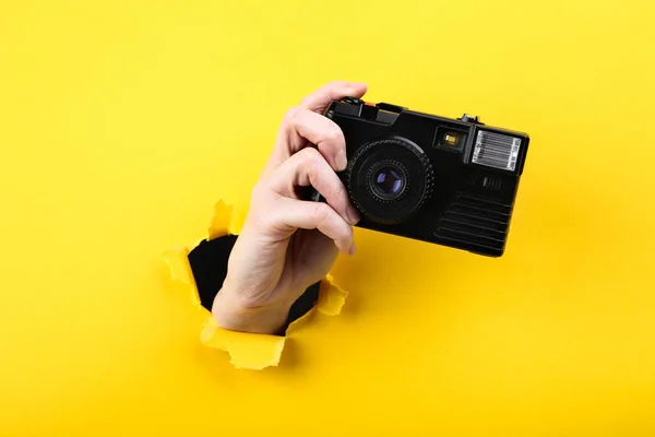 노란색 찢어진 종이에서 카메라를 들고 손을 잡고 — 스톡 사진