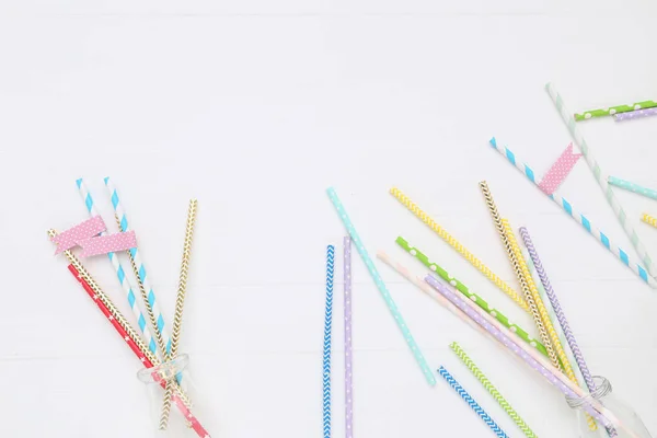 Colorful paper straws on white wooden table