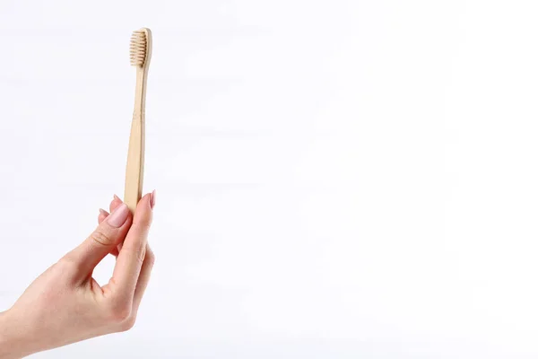 Bamboo toothbrush in female hand on white background — Stock Photo, Image