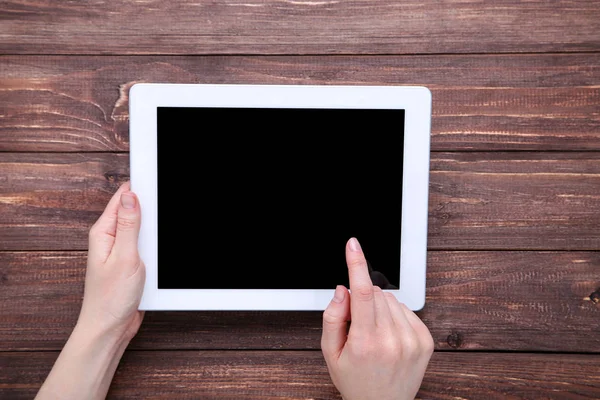 Komputer typu Tablet w kobiecych rękach na brązowym drewnianym stole — Zdjęcie stockowe