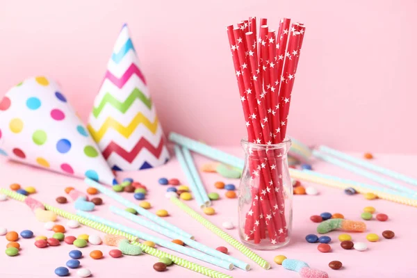 Papieren rietjes in glazen pot met snoepjes op roze achtergrond — Stockfoto