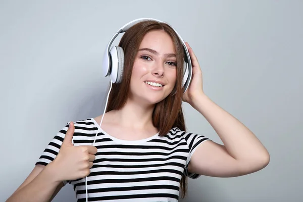 Mujer hermosa joven con auriculares sobre fondo gris — Foto de Stock