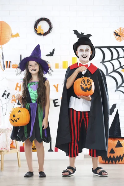 Chica joven y niño en trajes de halloween con cubos de calabaza —  Fotos de Stock