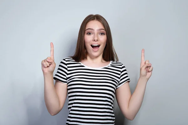 Mujer joven en camiseta a rayas sobre fondo gris — Foto de Stock