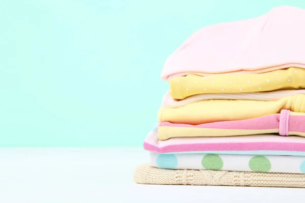 Different folded baby clothes on blue background — Stock Photo, Image