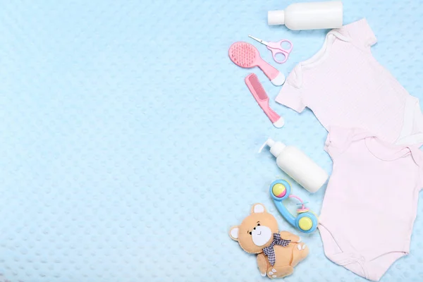 Mavi arka planda oyuncaklar ve bebek malzemeleri ile Giysi — Stok fotoğraf