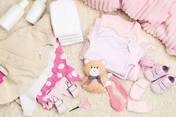 Pakaian dengan mainan dan perlengkapan bayi di karpet — Stok Foto