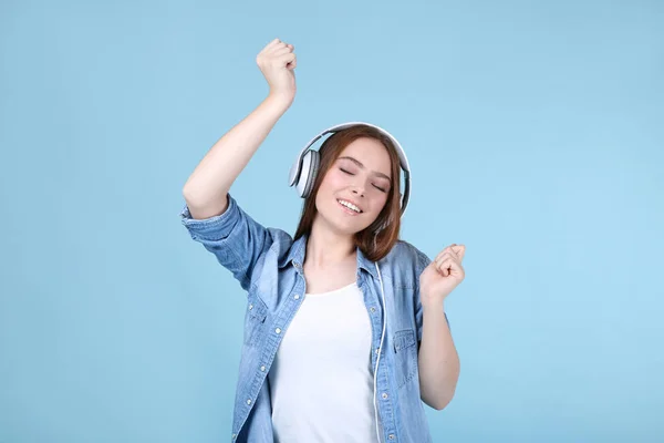 Jeune belle femme avec écouteurs sur fond bleu — Photo