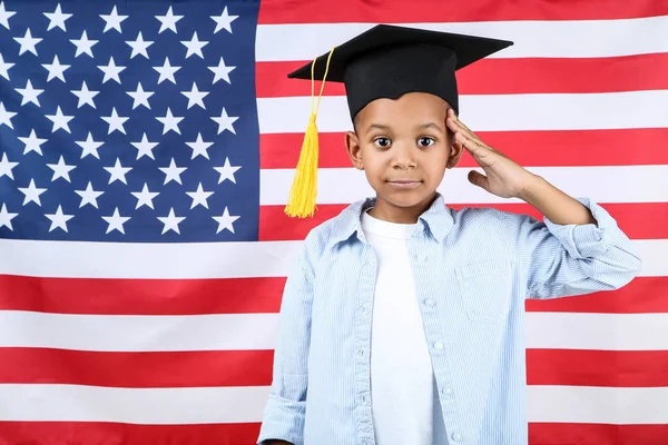 Lindo chico en gorra de graduación en fondo de bandera americana — Foto de Stock