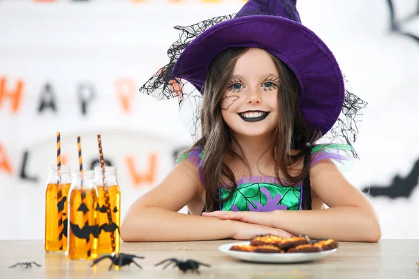 Mooi meisje in Halloween kostuum zittend bij de tafel — Stockfoto