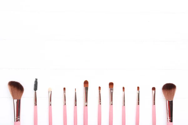 Set of makeup brushes on white wooden table — Stock Photo, Image