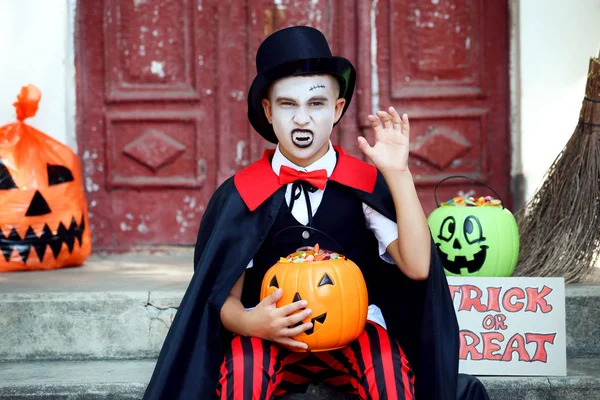 Niño en traje de halloween sosteniendo cubo de calabaza con candi — Foto de Stock