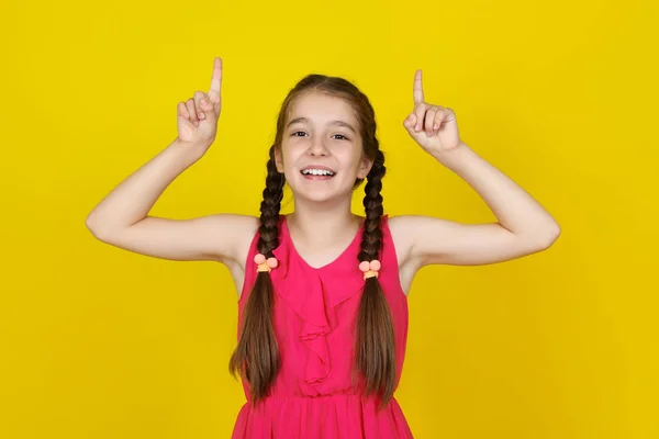 Menina bonita em vestido rosa mostrando os dedos no amarelo — Fotografia de Stock