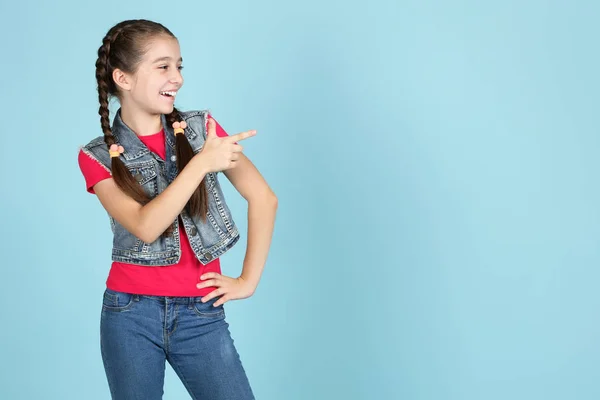 Menina bonita mostrando o dedo no fundo azul — Fotografia de Stock