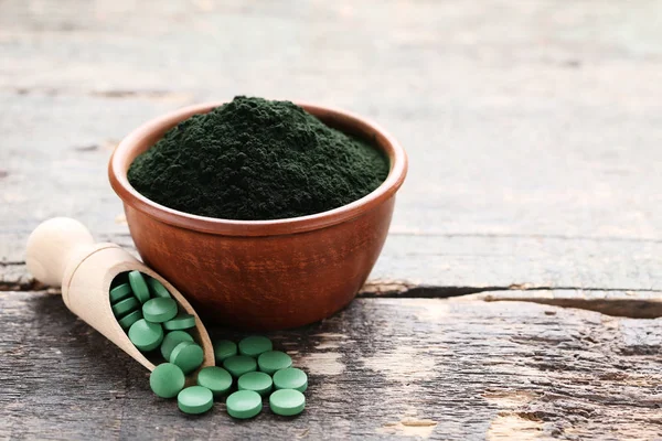 Spirulina w proszku i tabletki na drewnianym stole — Zdjęcie stockowe