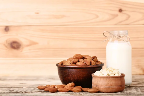 Almendra y leche en botella sobre mesa de madera marrón — Foto de Stock