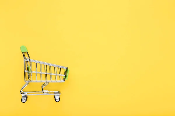 Carrito de compras pequeño sobre fondo amarillo —  Fotos de Stock