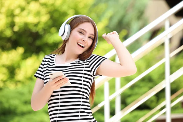 Mujer hermosa joven con auriculares y teléfono inteligente — Foto de Stock