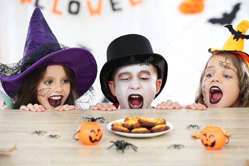 Young two girls and boy in halloween costumes looking on the coo