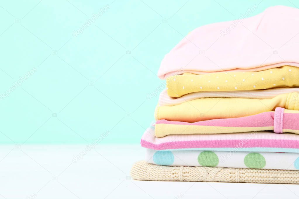 Different folded baby clothes on blue background