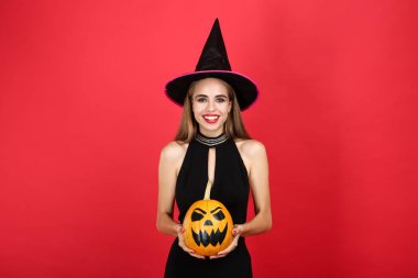 Siyah kostümlü güzel kadın üzerinde cadılar bayramı balkabağı tutan