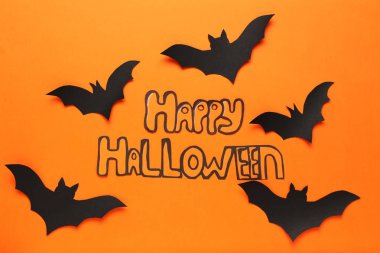 Turuncu arka planda metin Happy Halloween ile Kağıt yarasalar