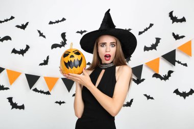 Siyah kostümlü güzel kadın cadılar bayramı balkabağı ile tutuyor 