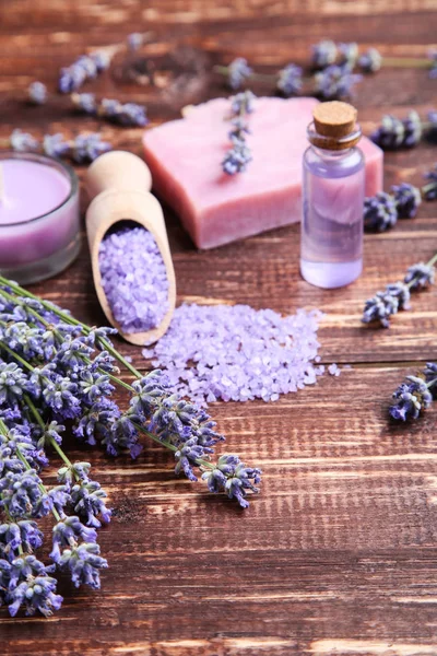 Lavendelblüten mit Öl in der Flasche, Salz und Seife auf braunem Holz — Stockfoto