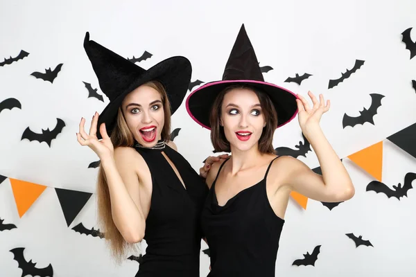 Two young women in black halloween costumes with paper bats and — Stock Photo, Image