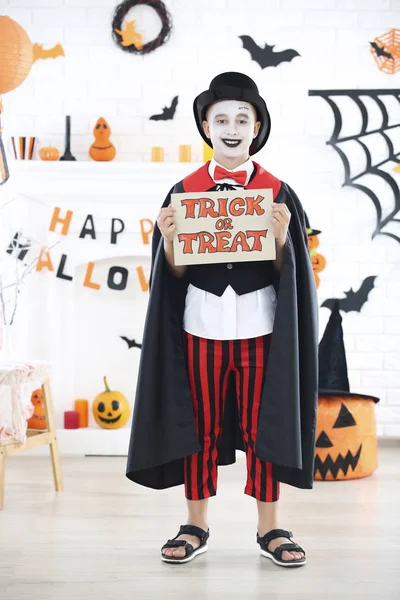 Niño en traje de Halloween sosteniendo papel con texto Truco o —  Fotos de Stock