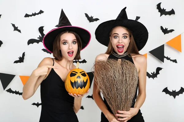 Duas jovens mulheres em trajes de Halloween com abóbora e vassoura em — Fotografia de Stock